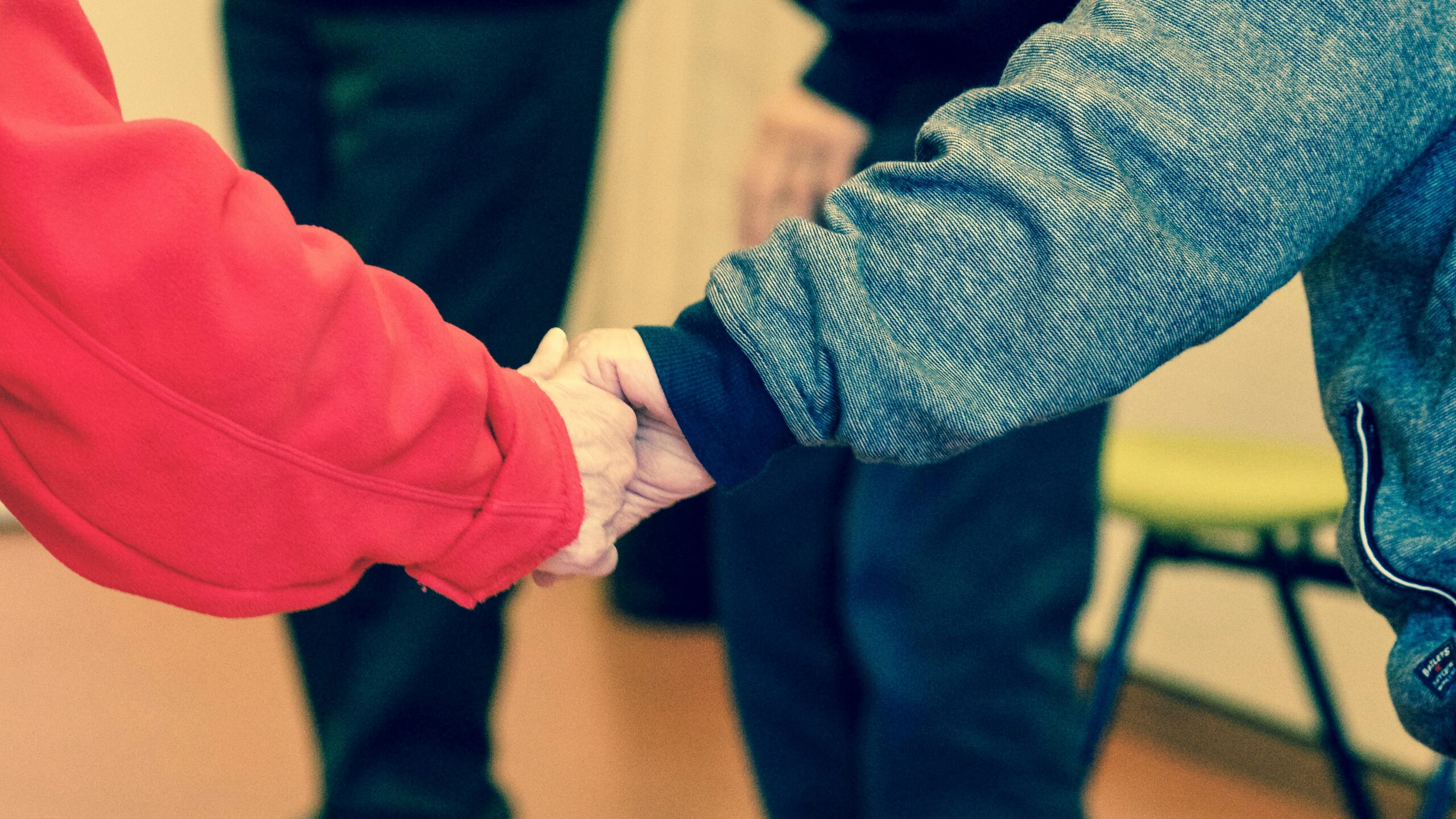 Close-up of elderly hands holding, symbolizing friendship and support indoors.