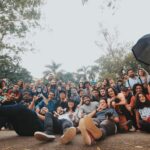 Ground level of multiethnic group of people gathering together near green plants and looking at camera